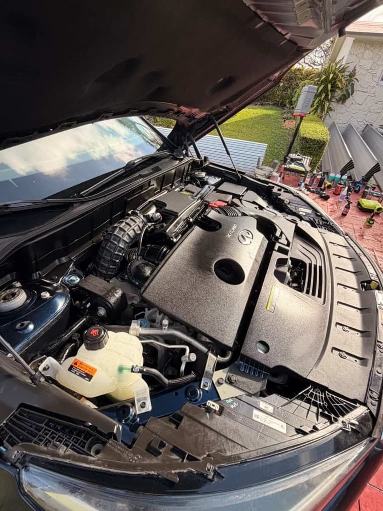 Clean Infiniti engine bay after detailing with products in background