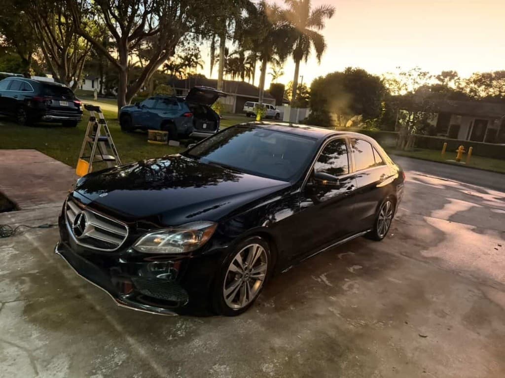 Black Mercedes-Benz E-Class sedan at golden hour on a residential driveway
